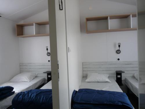 two beds in a small room with two tables at Camping Paradis Aloé in Médis