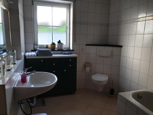 een badkamer met een wastafel, een toilet en een raam bij Ferienwohnung Thönnes in Müden