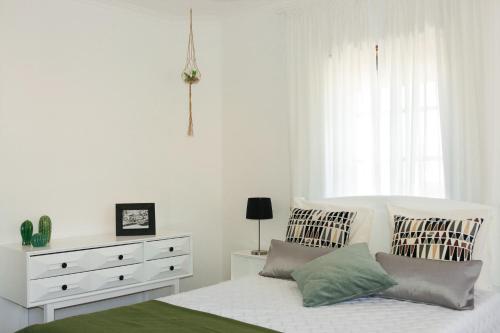 a white bedroom with a bed and a dresser at Ascensor House in Nazaré