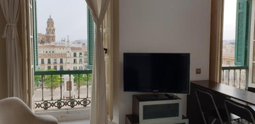 een woonkamer met een flatscreen-tv naast een raam bij Suncity Atico La Merced in Málaga