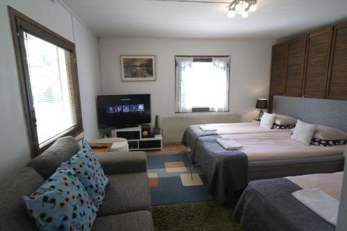 a bedroom with two beds and a couch and a tv at Naantali Holiday Home in Naantali