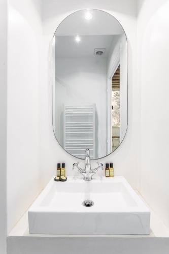La salle de bains est pourvue d'un lavabo et d'un grand miroir. dans l'établissement Habitat Parisien - 2BR-2BA - Marais - Hôtel de Ville, à Paris