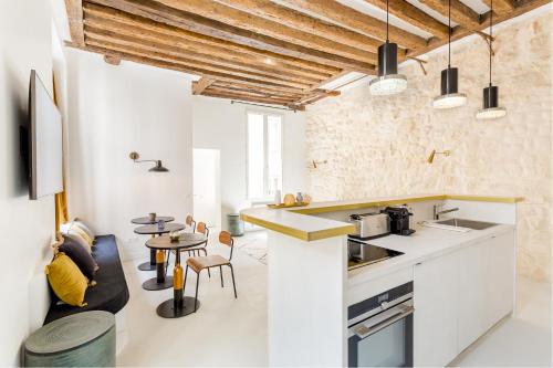 - une cuisine et un salon avec des comptoirs blancs et une table dans l'établissement Habitat Parisien - 2BR-2BA - Marais - Hôtel de Ville, à Paris