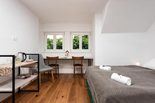 a bedroom with a bed and a desk and windows at Fani&Rozi B&B in Maribor