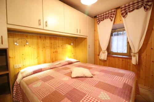 - une chambre avec un lit recouvert d'une couverture rose et brune dans l'établissement L'ermellino Bilocale in Centro - Affitti Brevi Italia, à Brusson