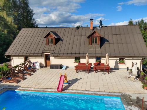 una casa con piscina frente a una casa en Chalupa Barborka - Národní park Krkonoše, sauna, bazén, dětské hřiště, gril, 6 pokojů, kuchyň, společenská místnost s krbem, en Vrchlabí