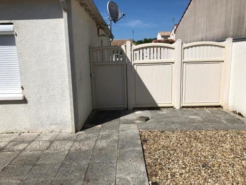 a white fence with a gate next to a house at St Georges de Didonne, Maison bien équipée au calme in Saint-Georges-de-Didonne