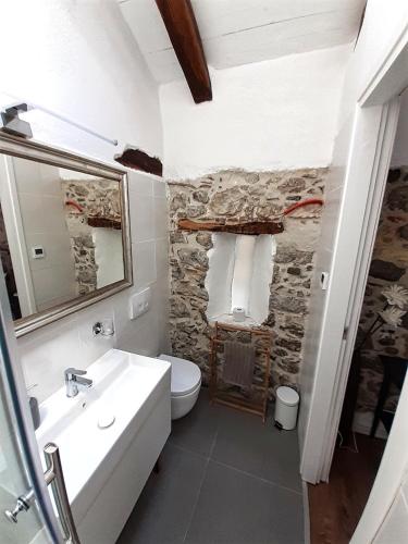 a bathroom with a white sink and a stone wall at Apartments Hemingway House in Kobarid