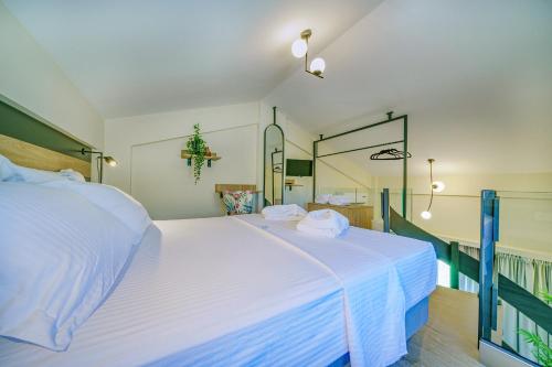 a bedroom with a large white bed with a mirror at Miroes Suites in Nikiti