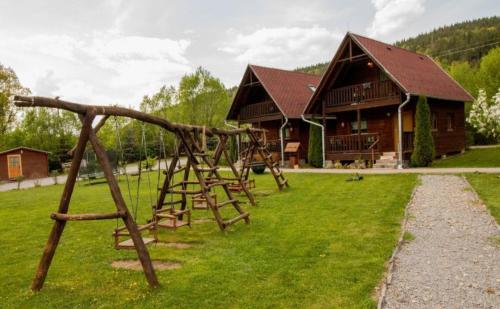 une aire de jeux en face d'une cabane en rondins dans l'établissement Irgó kulcsosházak, à Izvoare