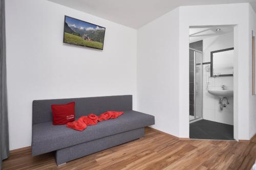 レンゲンフェルトにあるApart Alessandroのリビングルーム(赤い枕とグレーのソファ付)