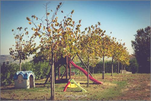 un parque infantil con un tobogán rojo y un árbol en Agriturismo Colle Tripio, en Guardiagrele