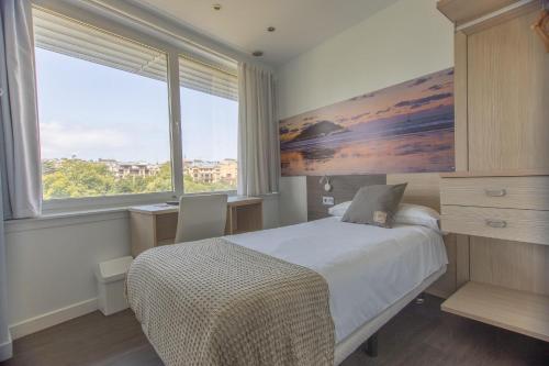 a bedroom with a bed and a large window at Pensión Riberas del Urumea in Donostia-San Sebastián