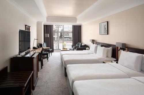 a hotel room with four beds and a television at Anwar Al Madinah Mövenpick in Al Madinah