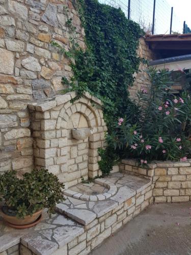 a stone wall with a brick oven in a garden at Schinas Apts. in Vitrinítsa
