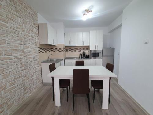 a white kitchen with a white table and chairs at Apartament Posada in Curtea de Argeş