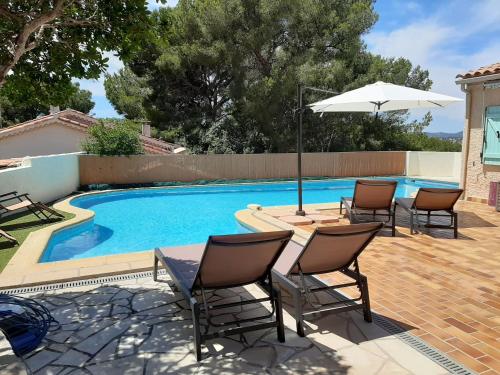 un patio avec des chaises et un parasol à côté d'une piscine dans l'établissement Villa avec grande piscine plage et port de Sanary à pieds, à Six-Fours-les-Plages