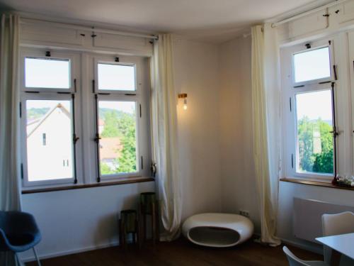 a room with three windows and a stool in it at Altes Forstamt in Gernsbach