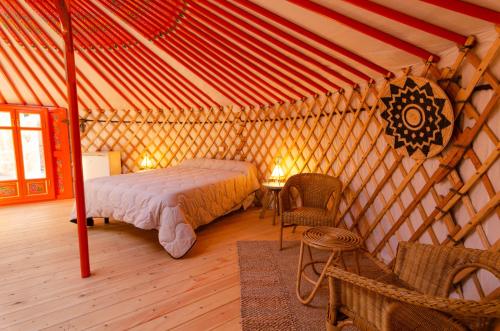 1 dormitorio en una yurta con 1 cama y 1 silla en Camping El Roble, en Valderrobres