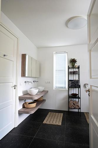 a white bathroom with two sinks and a window at De Lakenvelder B&B Eersel in Eersel
