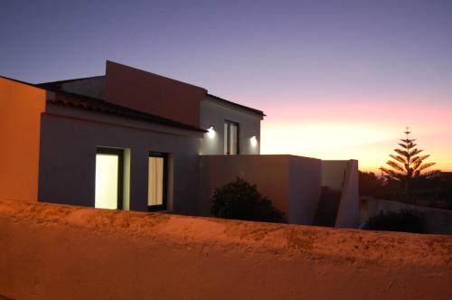 ein Haus, in dem die Sonne hinter einem Zaun untergeht in der Unterkunft Verde'Água Family Home in Mosteiros
