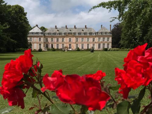 a large house with red roses in front of it at Château de Sissi in Sassetot-le-Mauconduit