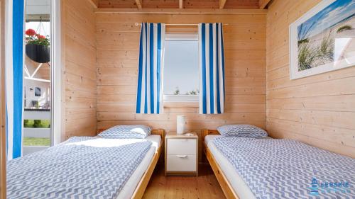two beds in a small room with a window at Łebskie Chatki in Łeba