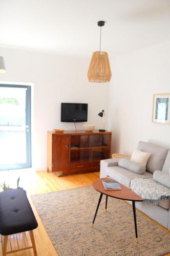 a living room with a couch and a tv at Verde'Água Family Home in Mosteiros