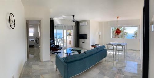 Fuentes de Nerja في نيرخا: غرفة معيشة مع أريكة زرقاء وطاولة
