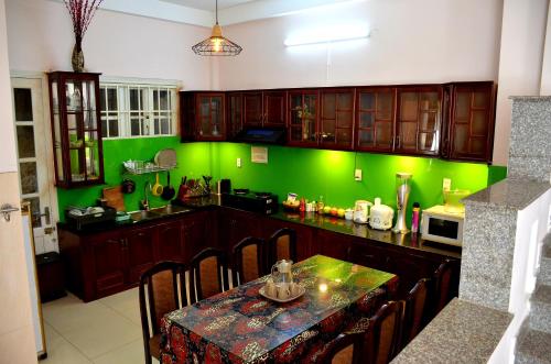 kuchnia z zielonymi ścianami i stołem z krzesłami w obiekcie Xen House w mieście Da Lat