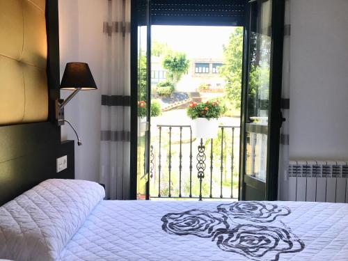 1 dormitorio con 1 cama y puerta a un balcón en Guest House El Padrino en Portomarin