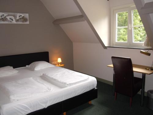 a bedroom with a bed and a desk and a window at Hotel Malcot in Mechelen