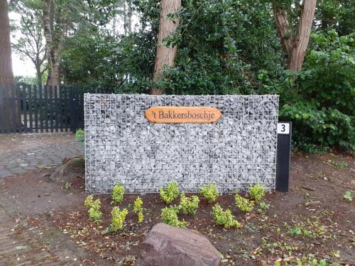 a sign on a stone wall in a park at t'Bakkersboschje nummer 11 in Putten