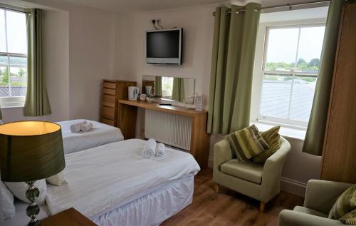 una habitación de hotel con 2 camas y una silla en The Angel Hotel, en Cardigan