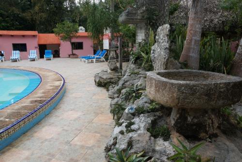 a large stone fountain next to a swimming pool at Hotel Doralba Inn Chichen in Chichén-Itzá