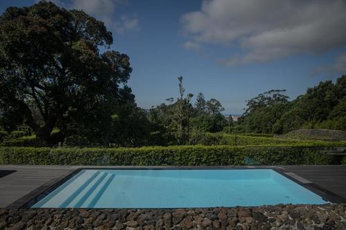 a swimming pool in the middle of a garden at Quinta dos 10 in Ponta Delgada