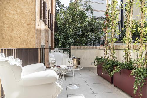 un patio con sillas blancas y una mesa en LEONI DI COLLALTO PALACE en Treviso