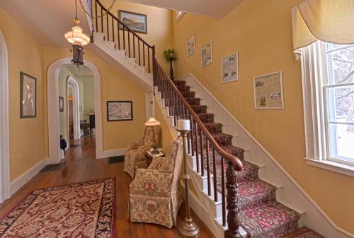 a hallway with stairs with chairs and a rug at The Bed and Breakfast at Oliver Phelps in Canandaigua