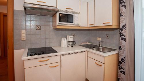 a small kitchen with white cabinets and a sink at Apart Bel Ami in Kappl