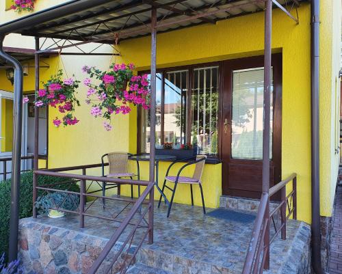 a patio with a table and chairs on a yellow house at Pas Birutę in Palanga