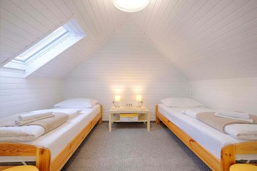 two beds in a room with a window and a table at Penzion Park in Laško