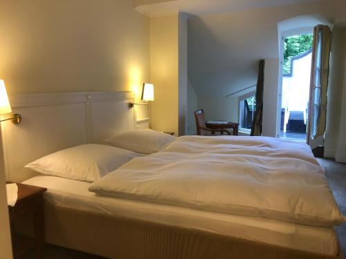 um quarto com uma grande cama branca e 2 almofadas em Hotel Scherf Residenz em Bad Lippspringe