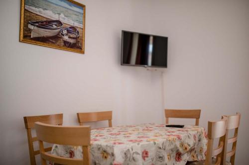 a dining room table with chairs and a tv on a wall at Paradise Apartments in Lopar