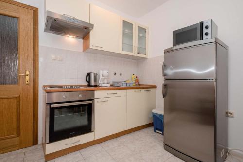 a kitchen with a stainless steel refrigerator and white cabinets at Paradise Apartments in Lopar
