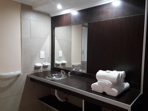ein Badezimmer mit einem Waschbecken, einem Spiegel und Handtüchern in der Unterkunft Ayres del Bosque in Merlo