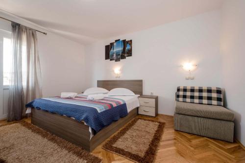 a bedroom with a bed and a chair at Paradise Apartments in Lopar