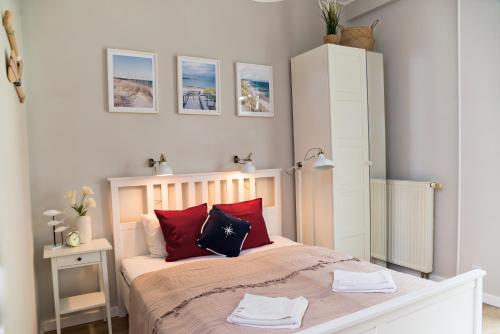 1 dormitorio con 1 cama con almohadas rojas y negras en Portofino Seaside Apartments, en Międzyzdroje