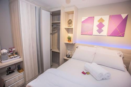 a bedroom with a white bed with towels on it at Studio Completo no Centro de Curitiba - ALL1021 in Curitiba