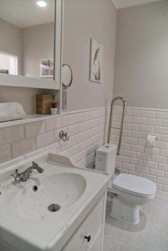 a white bathroom with a sink and a toilet at Portofino Seaside Apartments in Międzyzdroje
