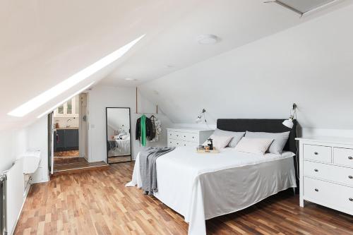 a white bedroom with a white bed and a mirror at Cozy Apartment in Uppsala